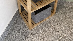 A wooden shelf unit with a potted plant on top, a folded towel, and a storage bin. - Ferienhaus Hopfental (Kelheim)