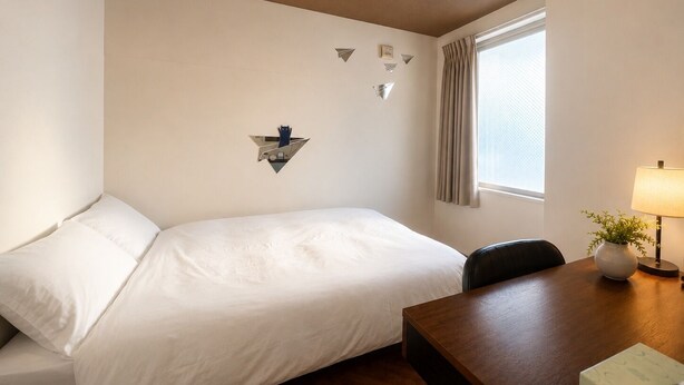 A hotel room with a bed, a desk, a chair, a lamp, and a window with curtains. - Hotel Wan Osaka ebisu (Osaka)