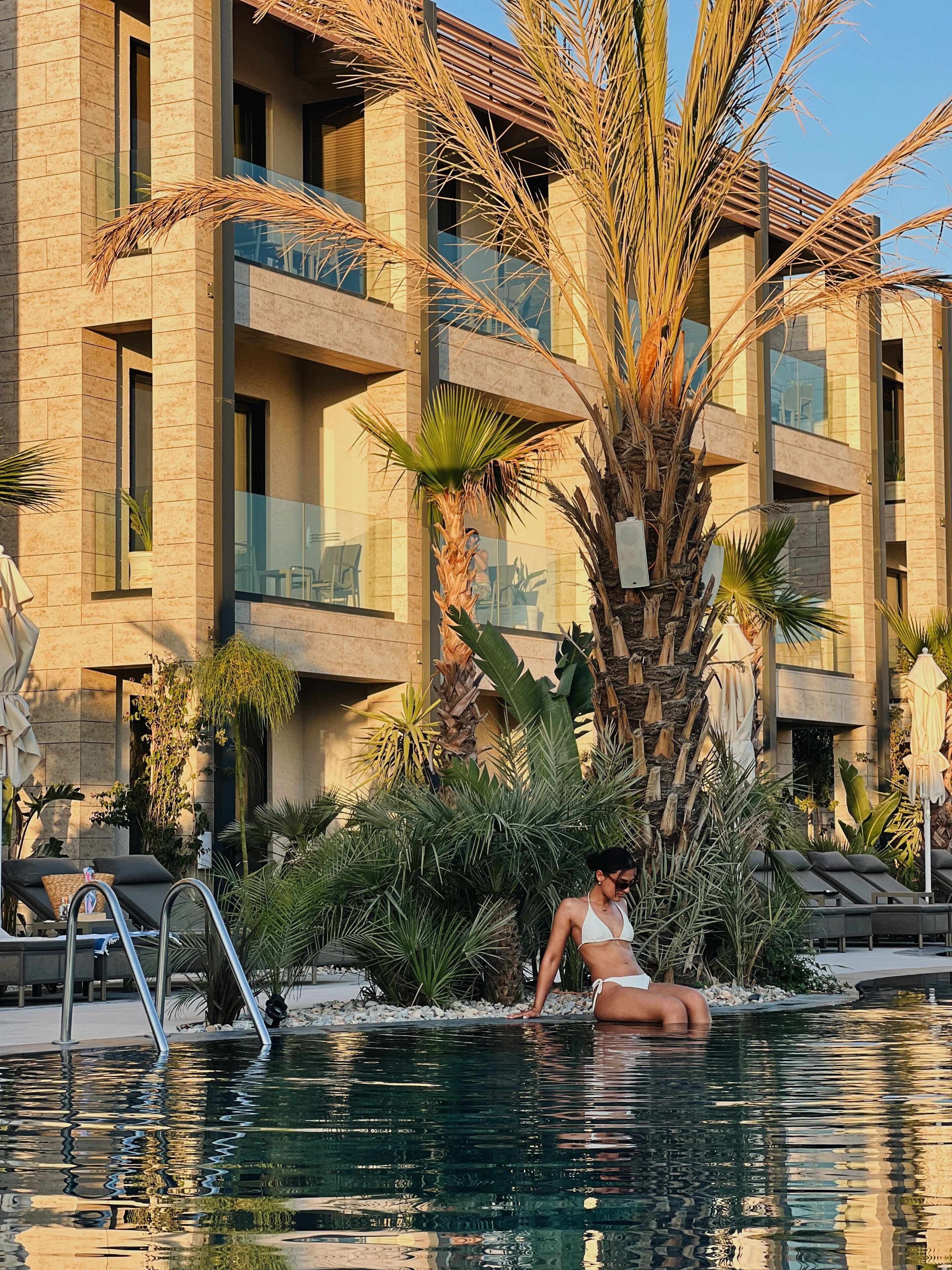 Una piscina al aire libre, sombrillas, sillones reclinables de piscina