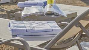 A beachside setting with lounge chairs, umbrellas, and a table with a book and a drink. - Rammos Managed by Dedeman  (Bodrum)