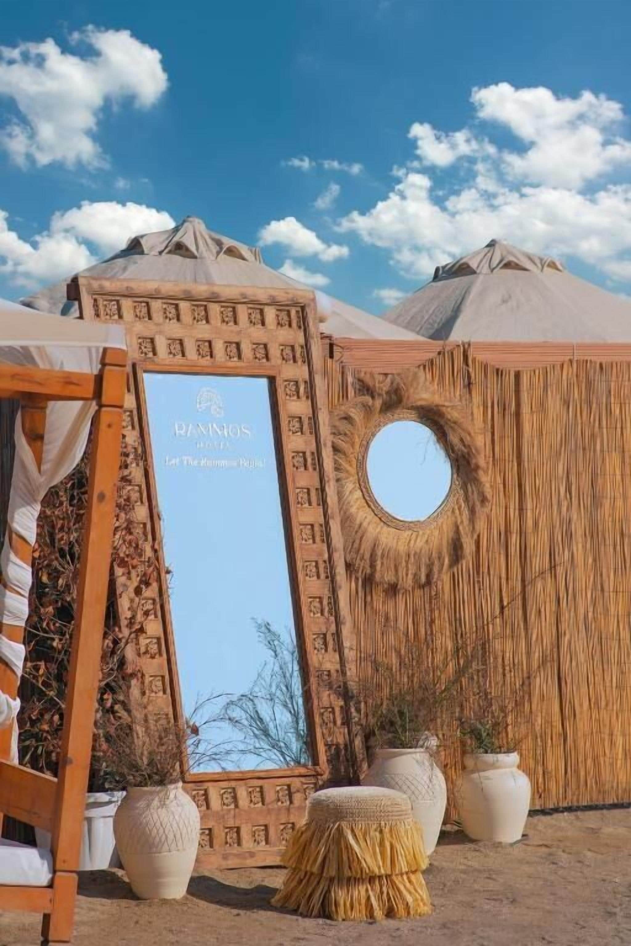 Una yurta tradicional con una abertura circular, estructura de madera con tallas intrincadas y un letrero que dice "RANISOS HOTEL Let The Adventure Begin!".