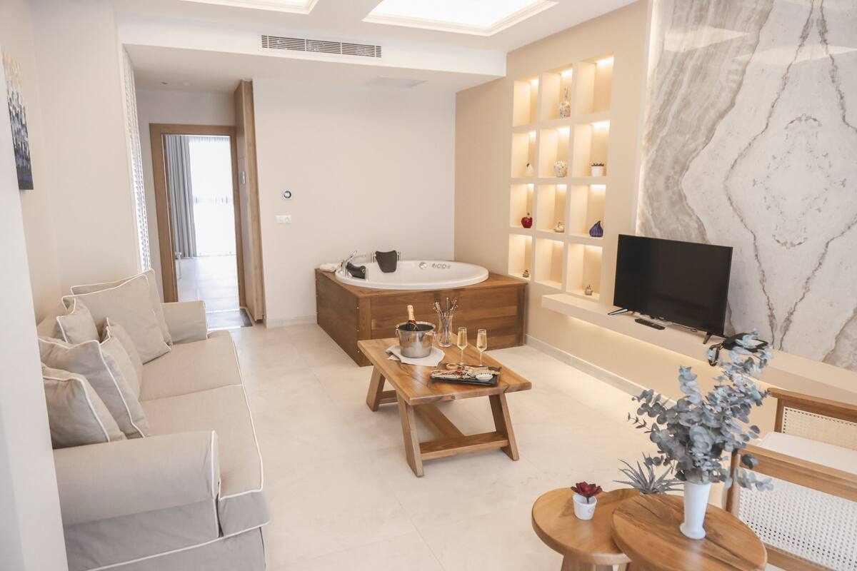 Una sala de estar moderna con un sofá, una mesa de centro de madera, un televisor y una pared de mármol.