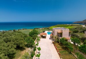 Une maison moderne avec piscine, entourée d’une végétation luxuriante et offrant une vue sur la mer.