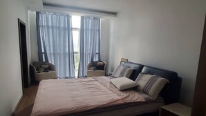 A bedroom with a bed, two nightstands, a dresser, and a window with curtains.