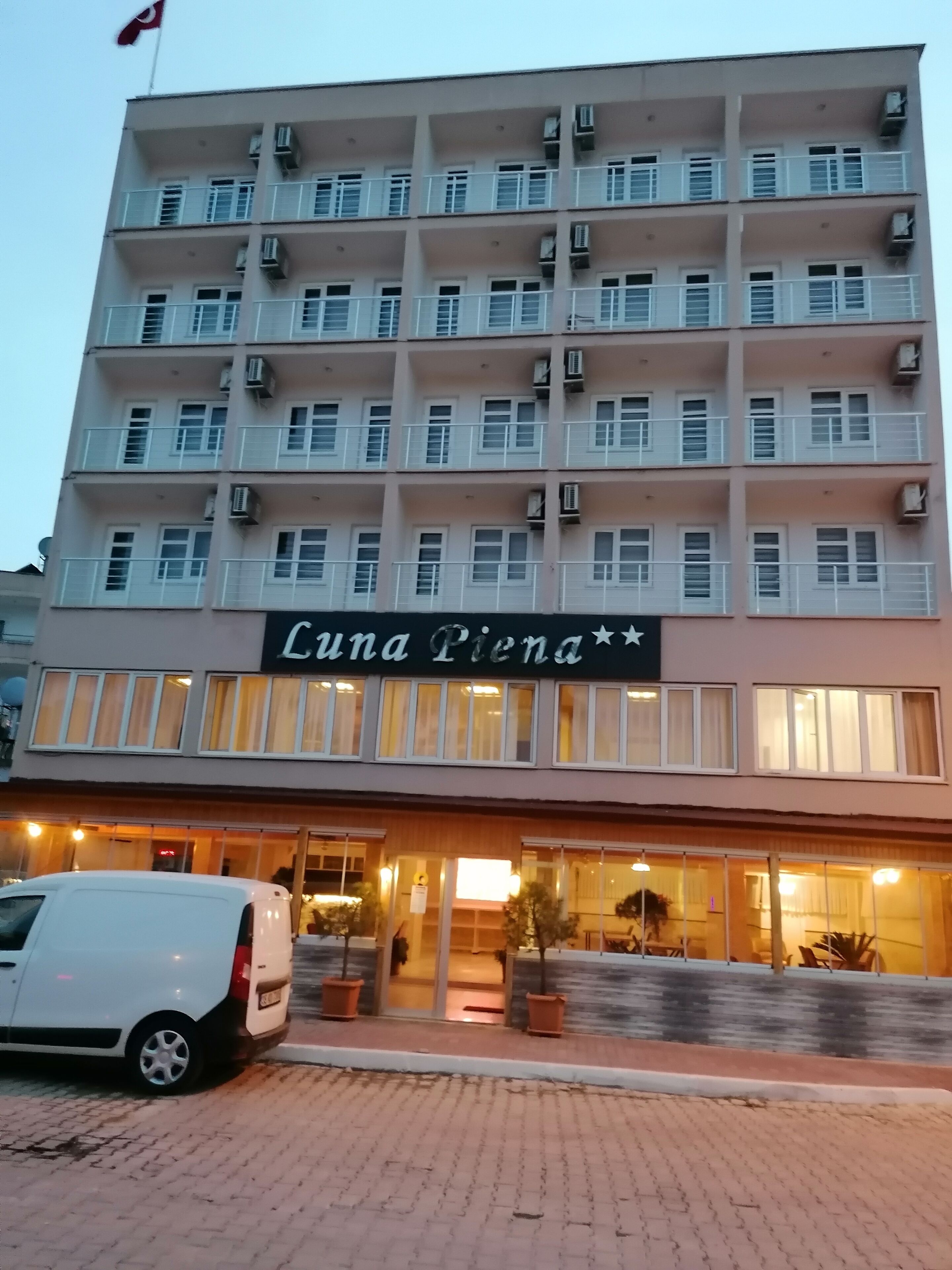 A multi-story hotel named Luna Piona with a modern facade, air conditioning units, and a well-lit entrance.