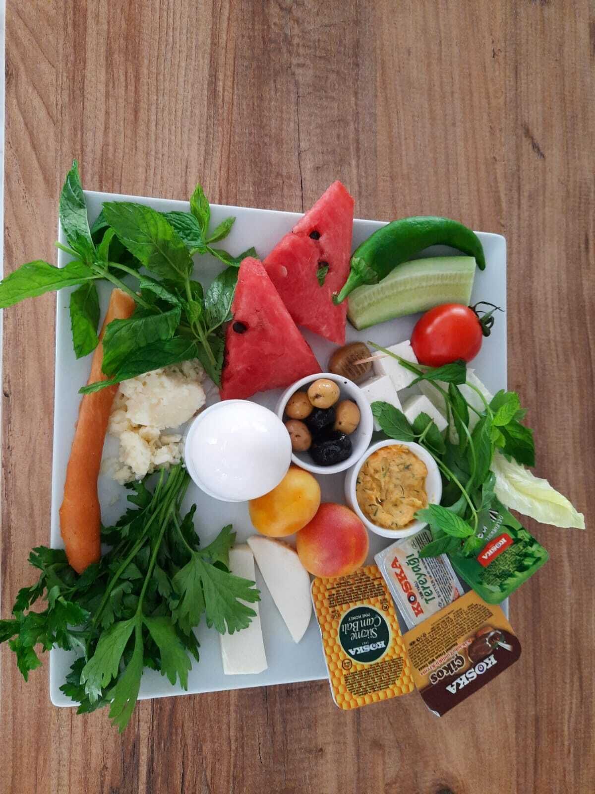 Un plato de comida con sandía, pepino, tomate, queso y aceitunas.
