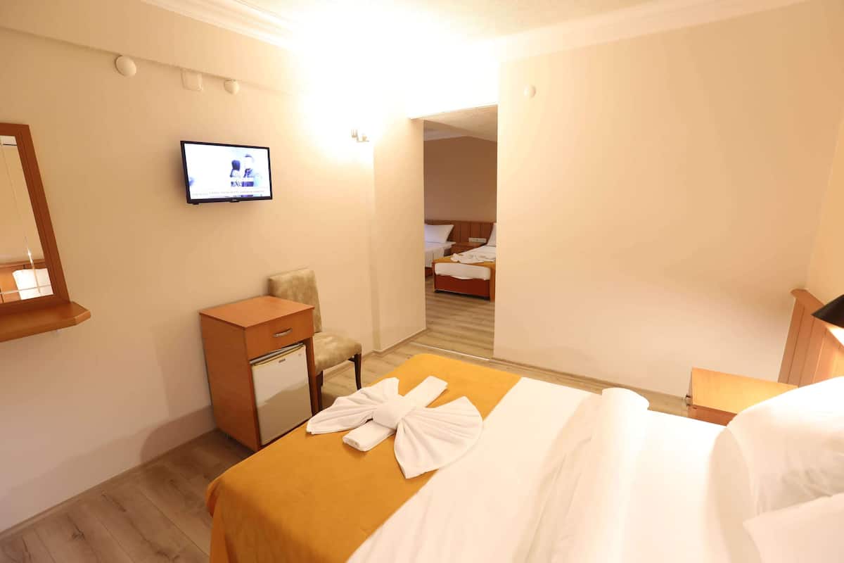 A hotel room with a bed, a TV mounted on the wall, a desk with a chair, and a small refrigerator.