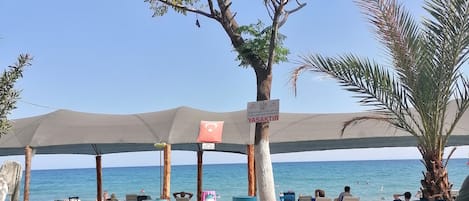 Privéstrand vlakbij, ligstoelen aan het strand, parasols, een strandbar