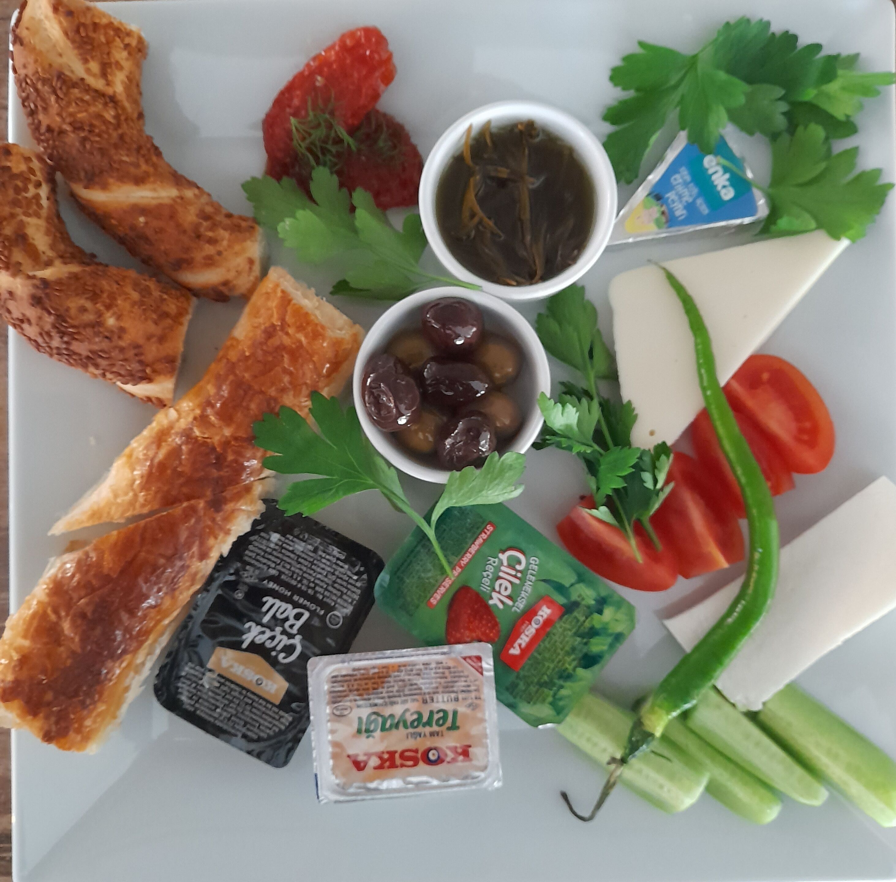 A plate with various food items including toast, strawberries, olives, cheese, and vegetables.
