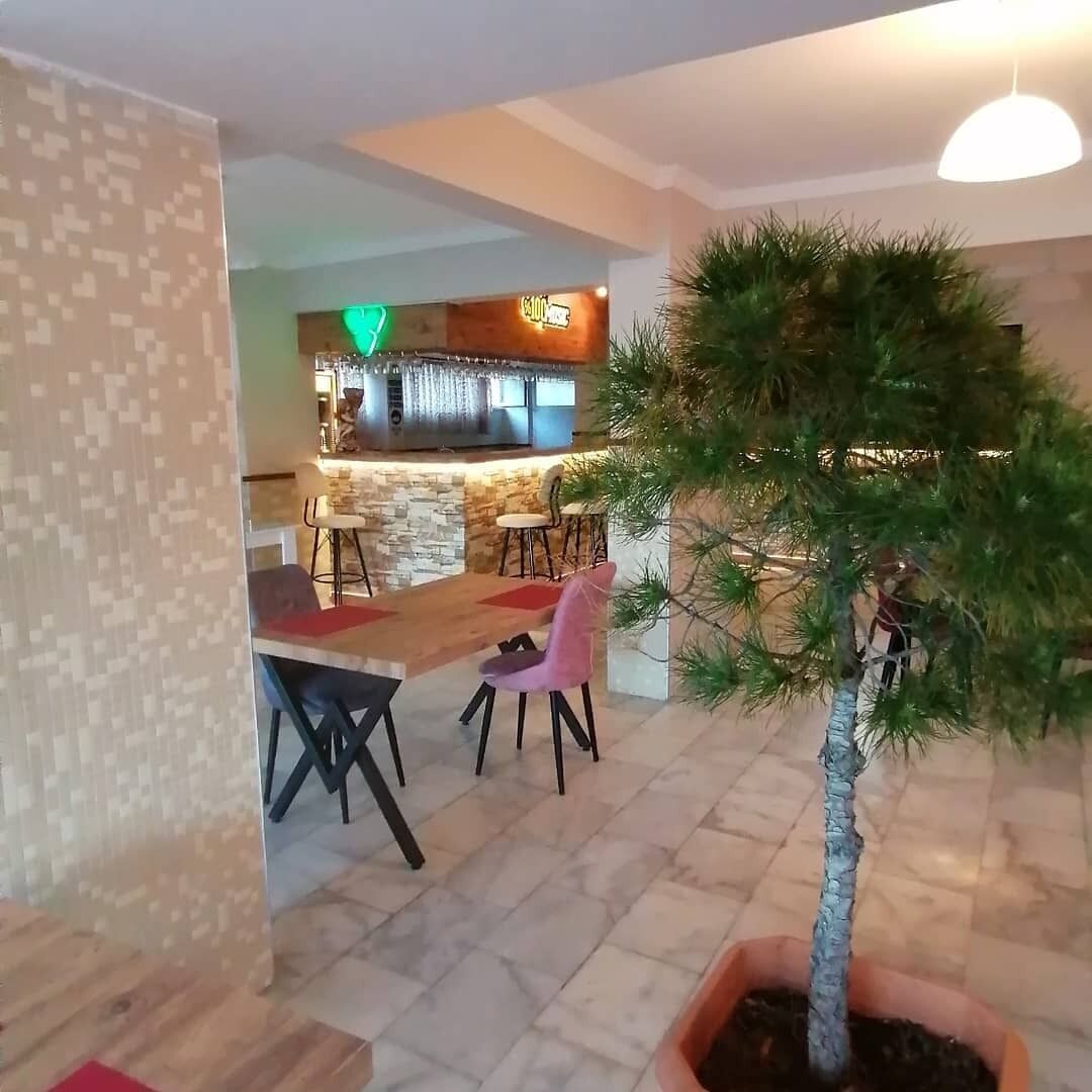 En modern inredning med ett matområde, en bar och ett träd i en kruka.