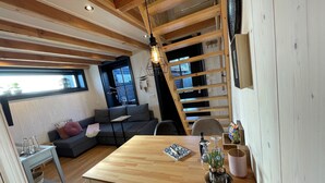 Un salon chaleureux avec une table à manger en bois, un canapé gris et un escalier.