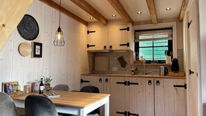 Une cuisine avec des meubles de rangement en bois, une table à manger et un luminaire suspendu.