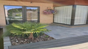 Un edificio moderno con fachada de ladrillo, grandes puertas de cristal y un pequeño jardín con una palmera.