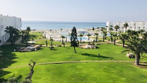 Un complexe hôtelier doté d’une piscine, de palmiers et offrant une vue sur la mer.