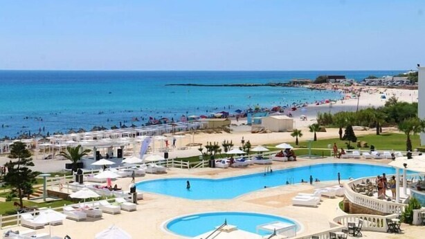 Un complexe hôtelier doté d’une grande piscine, d’une plage et d’une mer d’un bleu limpide.