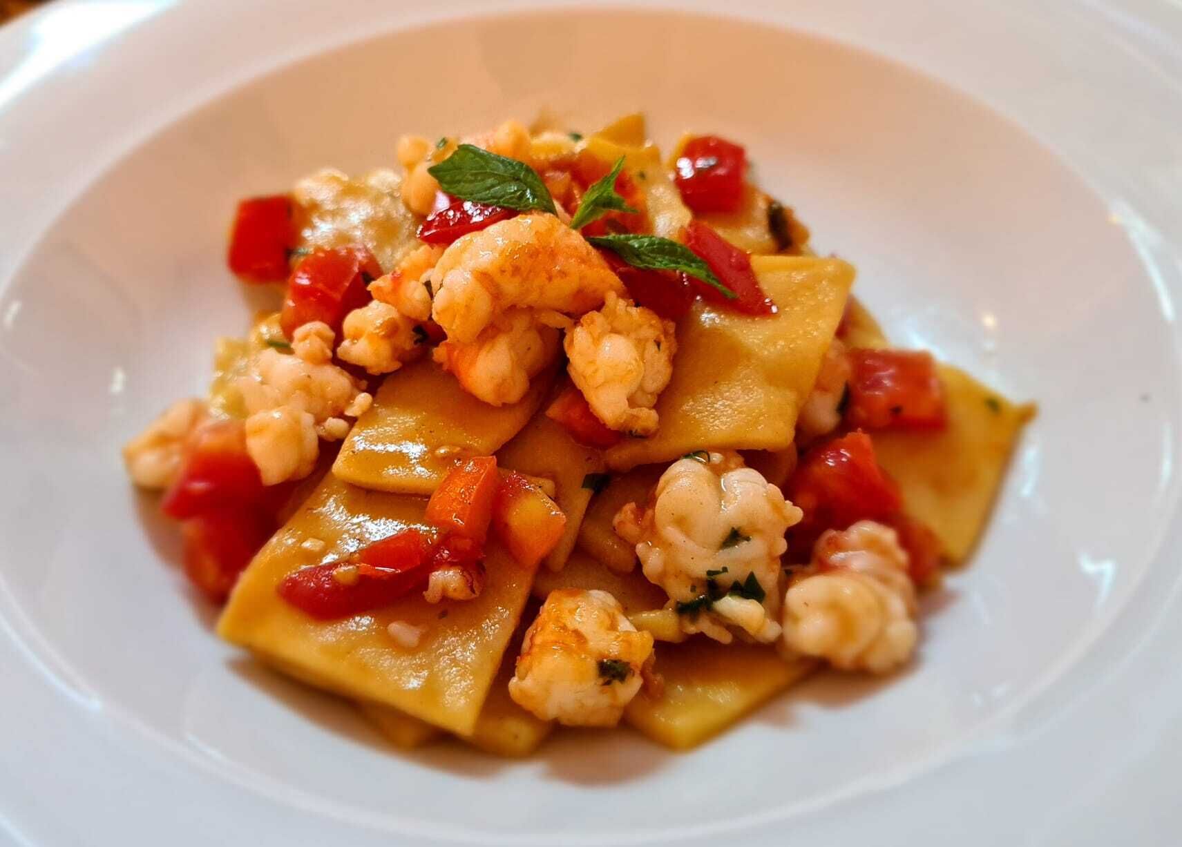 A plate of ravioli with vegetables and a garnish.