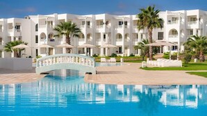 Un hôtel doté d’une piscine, d’un pont et de palmiers.