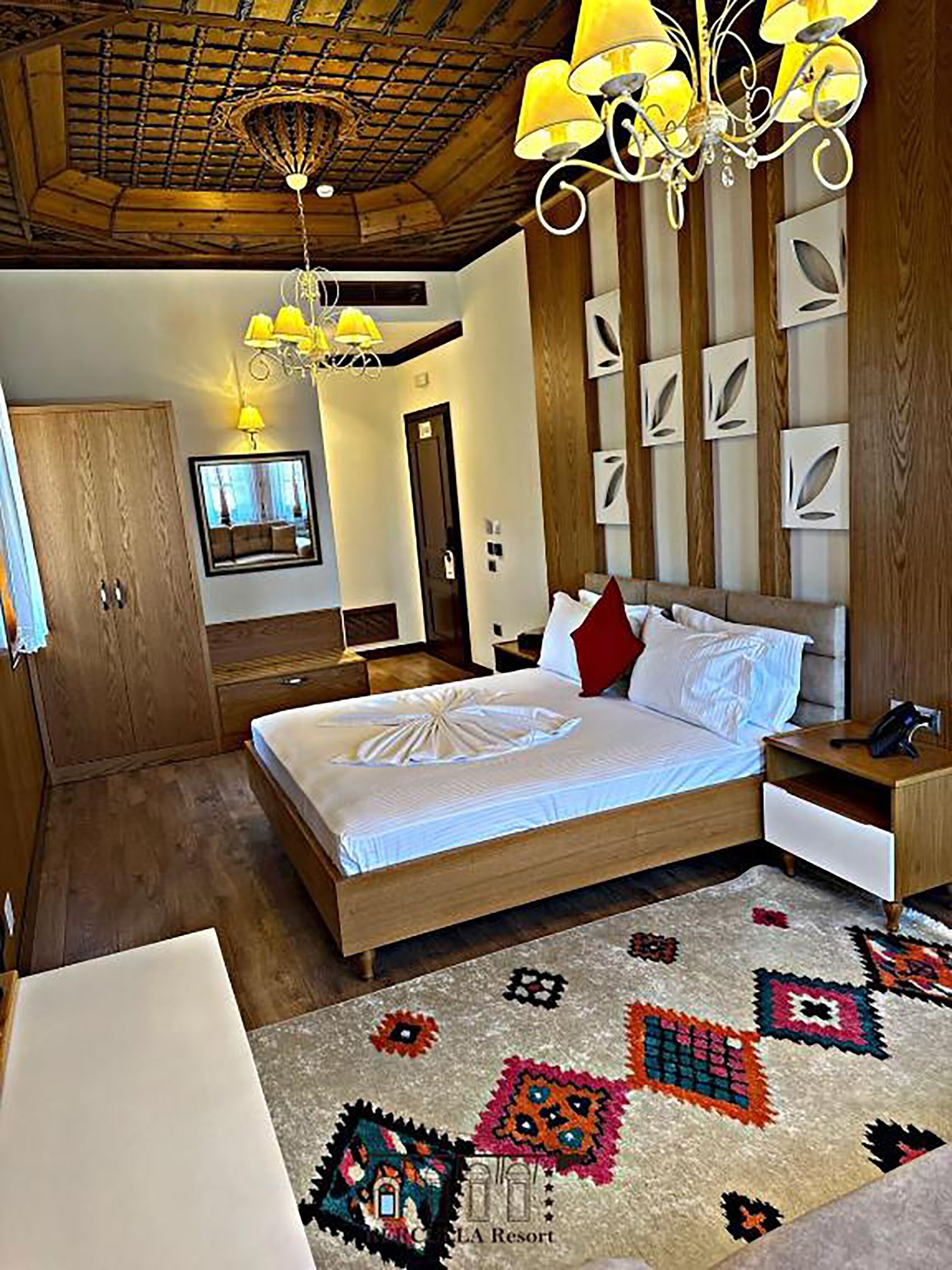 A bedroom with a wooden bed, a nightstand, a desk, and a chandelier.