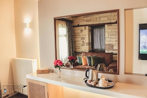 A modern kitchen with a stone wall backsplash, a white countertop, and a cozy seating area with a sofa and cushions.