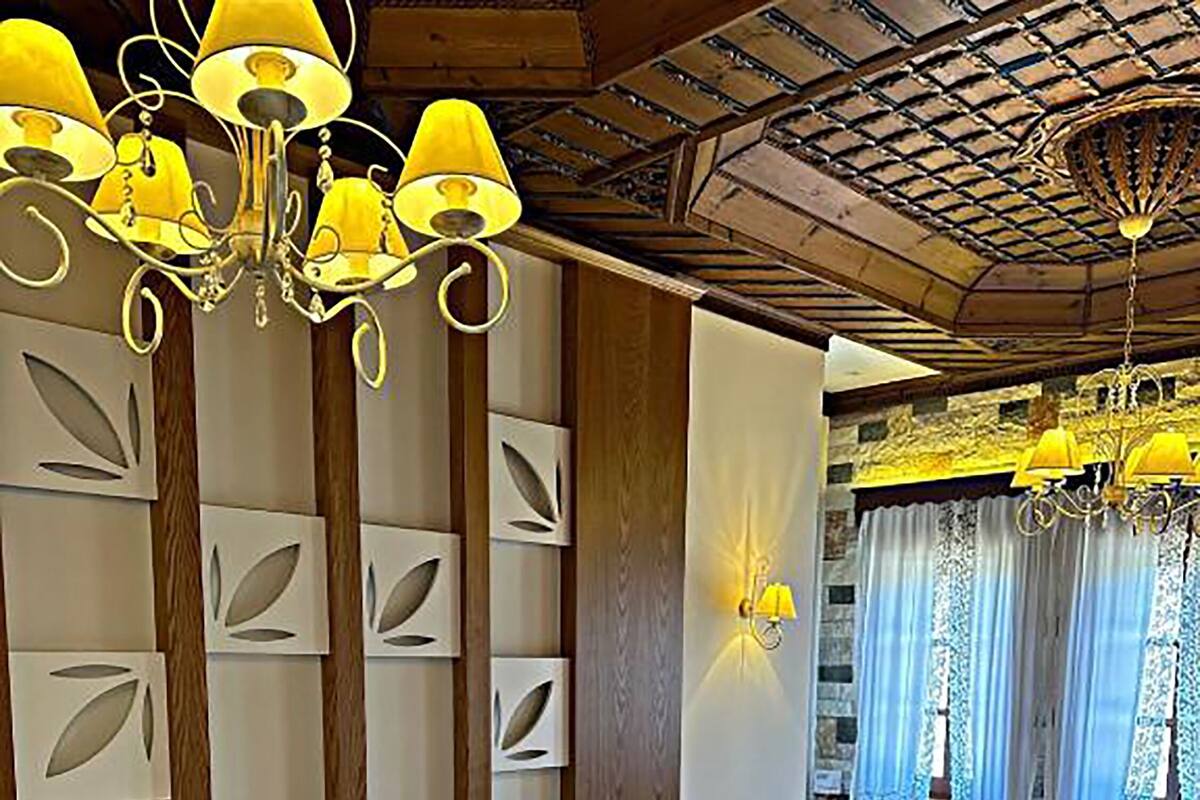 Una habitación de hotel con una cama grande, techo de madera, candelabro y un sofá.