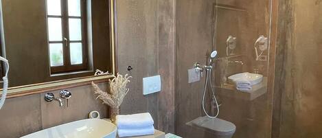 Un baño con un espejo grande, un lavabo, un inodoro y una ducha.