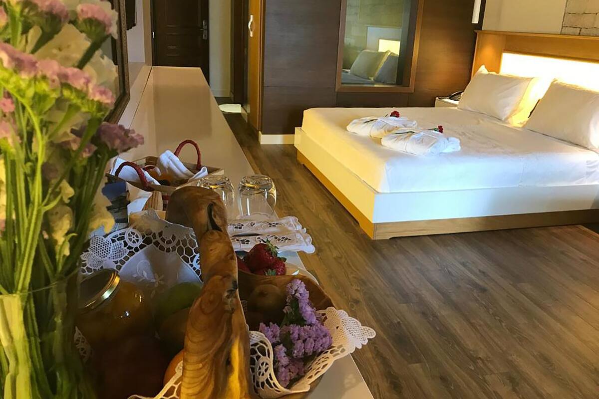 Habitación de hotel con cama, mesita de noche y vista al pasillo.