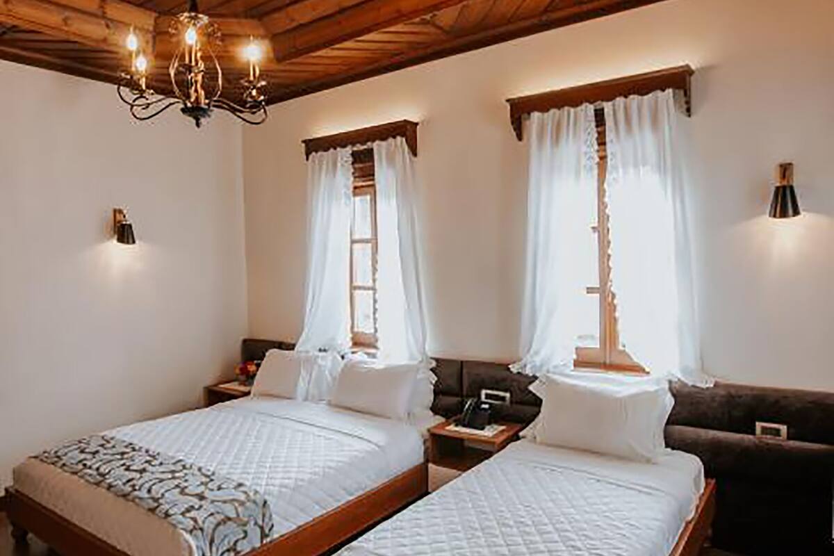 Una habitación con dos camas de madera, un candelabro y un sofá.