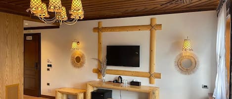 A room with a wooden ceiling, a TV mounted on a wooden frame, and a wooden bench with a small table.