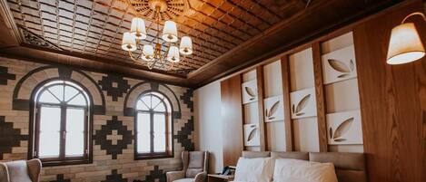A bedroom with a large bed, two armchairs, a wooden headboard, a chandelier, and patterned walls.