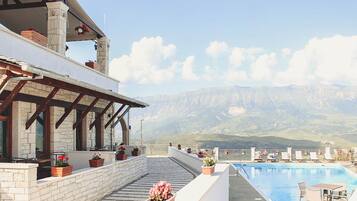 Um hotel com piscina, área de estar externa e vista para as montanhas.