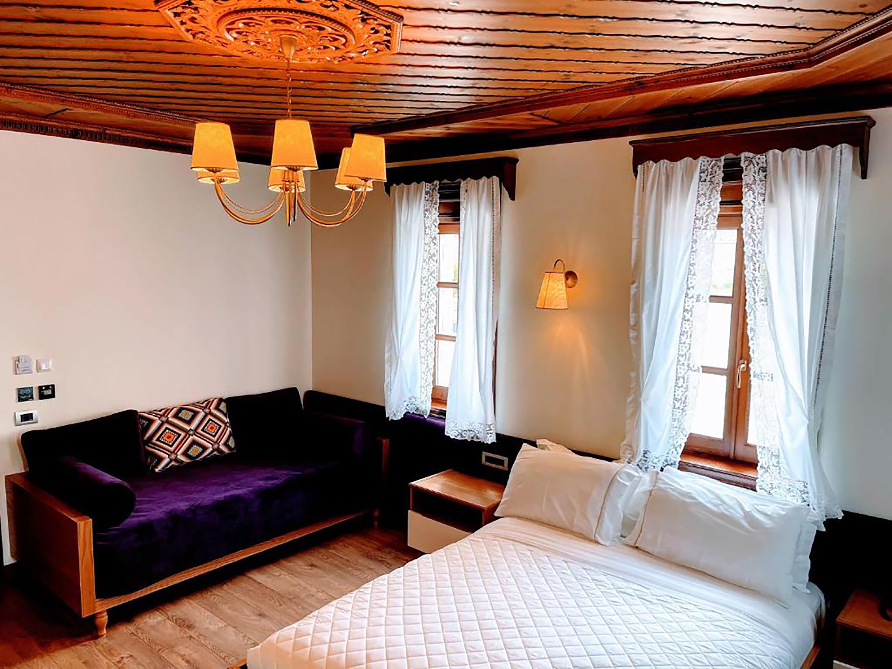 Una habitación con una cama, un sofá morado y un techo de madera.