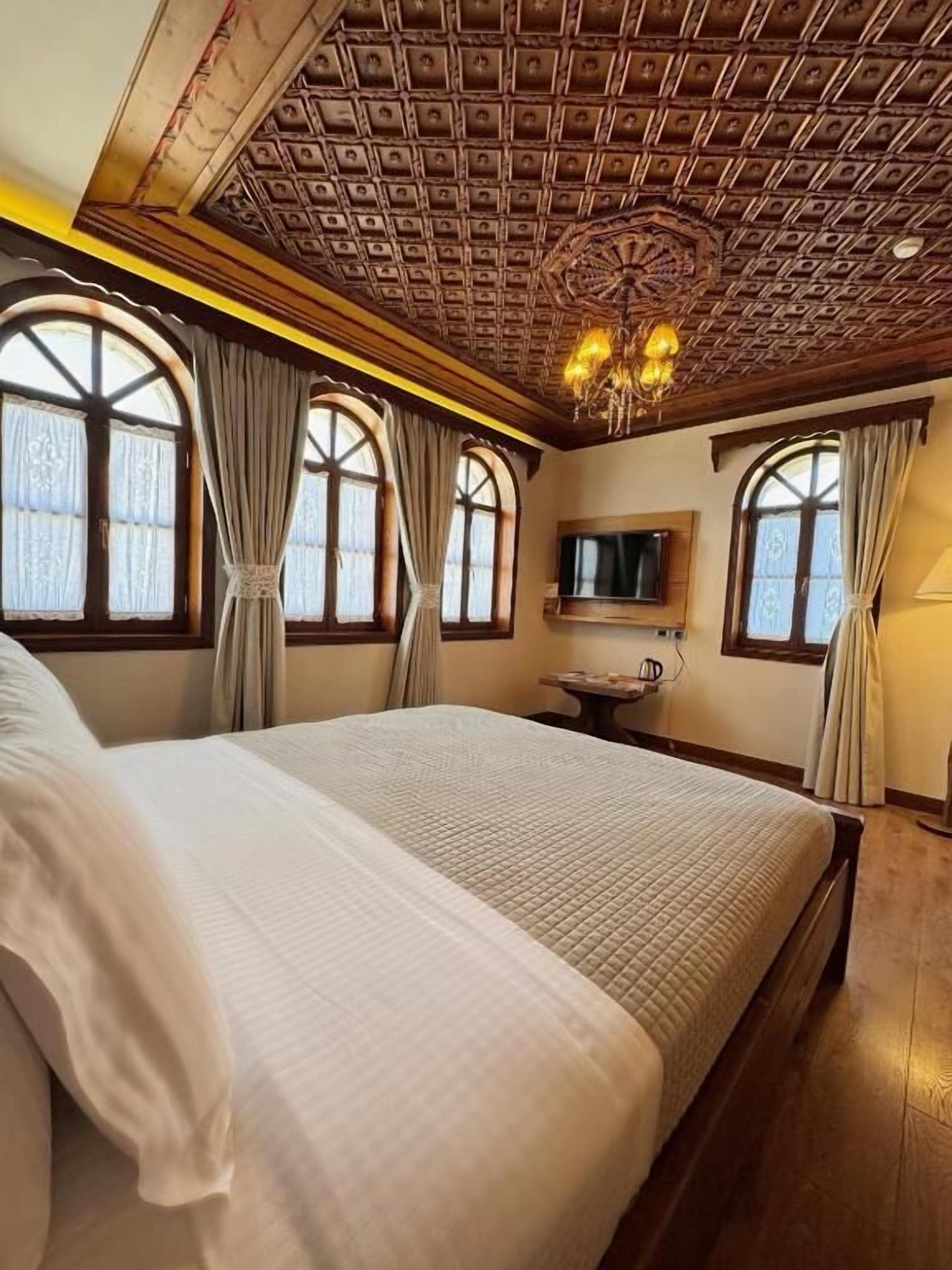 A bedroom with a large bed, a television, and a chandelier.