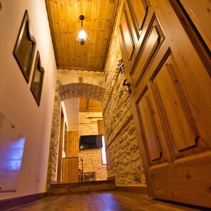 A wooden interior with a stone archway, wooden cabinets, and a hanging light fixture.