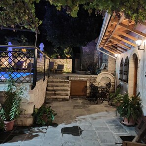 A stone patio with outdoor seating, a pool, and a stone wall. - Hotel Praga (Gjirokastër)