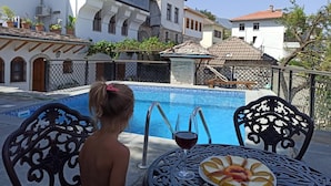 Ein Poolbereich mit Tisch und Stühlen, einem Glas Rotwein und einer Obstplatte.