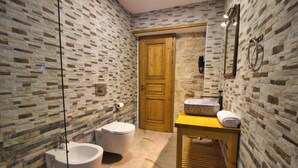 Ein Badezimmer mit Steinwand, Holztür, Waschbecken mit Granitplatte und Spiegel.