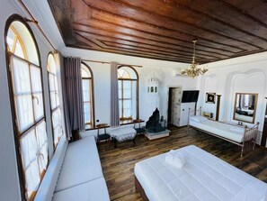 A room with a large bed, a bench, a fireplace, and a mirror. - Hotel Praga (Gjirokastër)