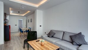 A modern living room with a sofa, a coffee table, and a dining area with chairs and a table. - Modern two bedroom apartment (Ronda)