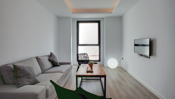 A modern living room with a sofa, a coffee table, a TV, and a large window. - Modern two bedroom apartment (Ronda)
