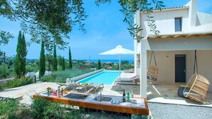 Una vila moderna amb piscina, zona d'estar a l'aire lliure i vistes al mar.