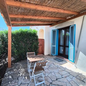 A patio with a wooden pergola, a stone table, and chairs.