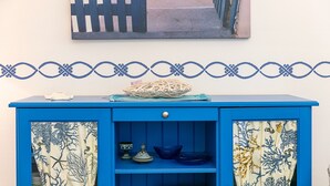 Un meuble bleu orné d’un rideau décoratif, avec un bol et une petite plante posés sur le dessus.