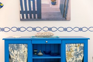 A blue cabinet with a decorative curtain, a bowl, and a small plant on top.