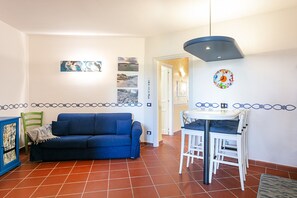 A living area with a blue sofa, a white table with chairs, and a ceiling light fixture.