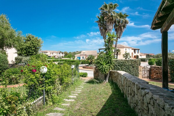 A residential area with stone walls, a pathway, and houses with tiled roofs.