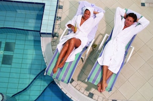 Dos sillones de exterior junto a una piscina con suelo de baldosas.
