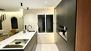 A modern kitchen with a central island, a built-in oven, and a large window. - Villa Vega with Pool, Garden & Wi-Fi (Alfaz del Pi)