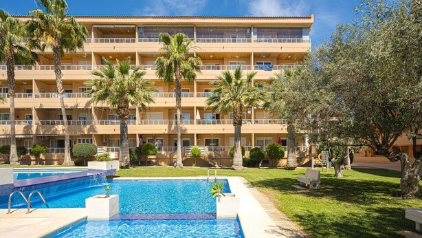 Un hôtel doté d’une piscine, de palmiers et d’un immeuble à plusieurs étages.