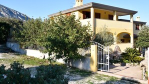 Une maison à deux étages avec un balcon, une porte et une montagne en arrière-plan.