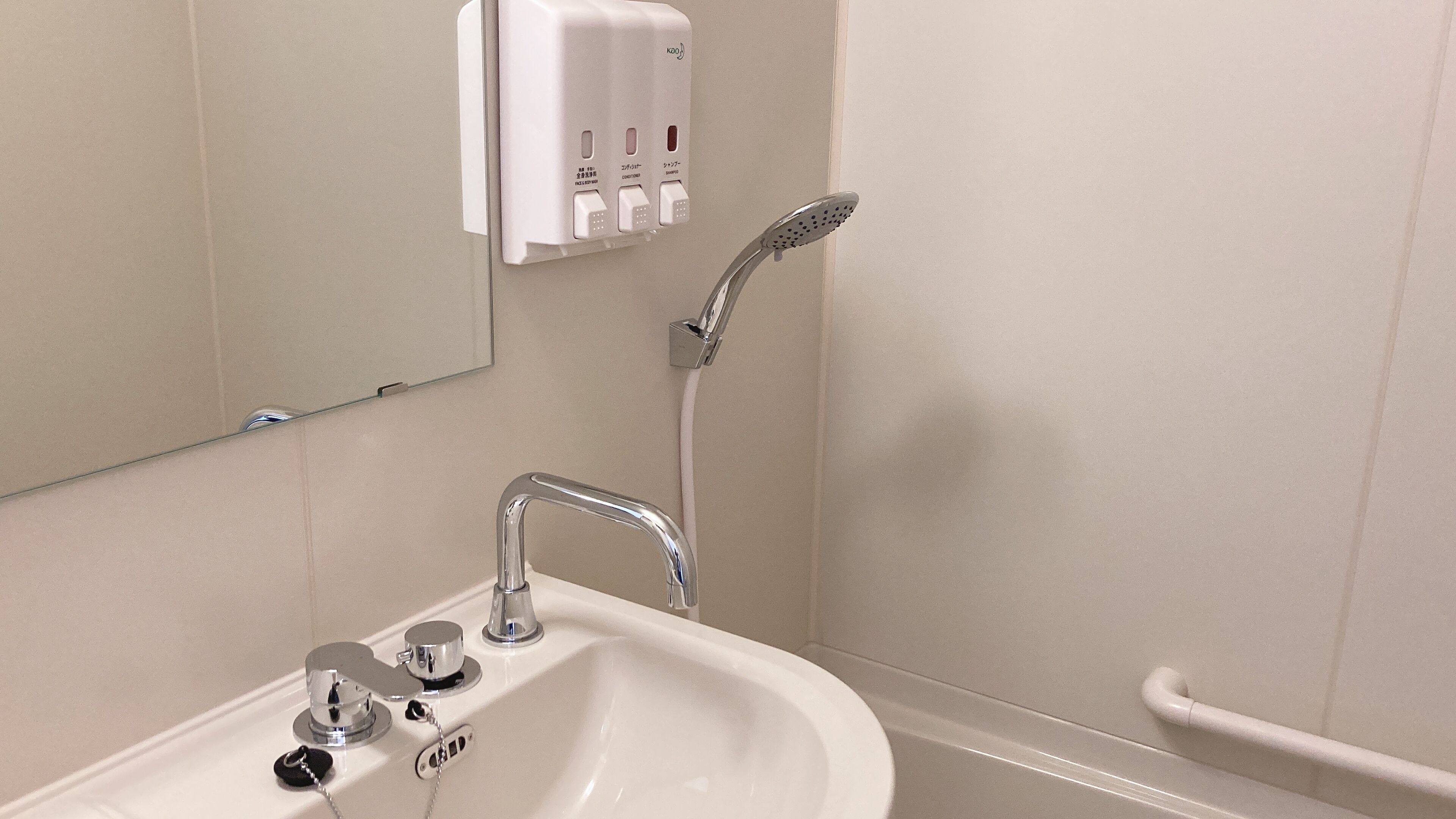 Un bany amb un lavabo, mirall i plat de dutxa manual.